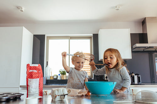 Siblings making cake in kitchen