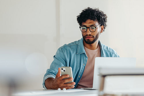 Young businessman using a smartphone to read a text message in office