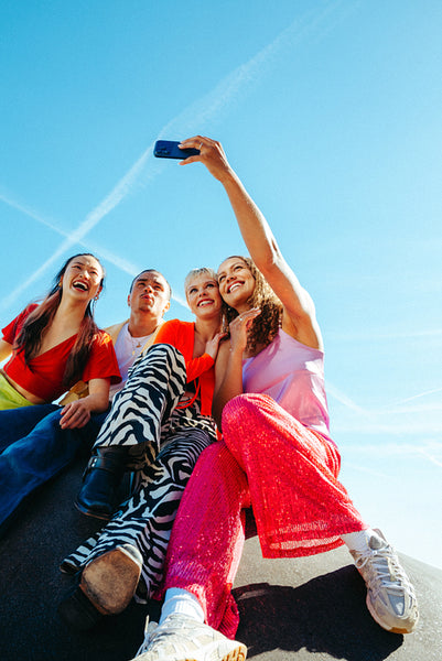 Phone brings friends together for a selfie outdoors under a clear blue sky