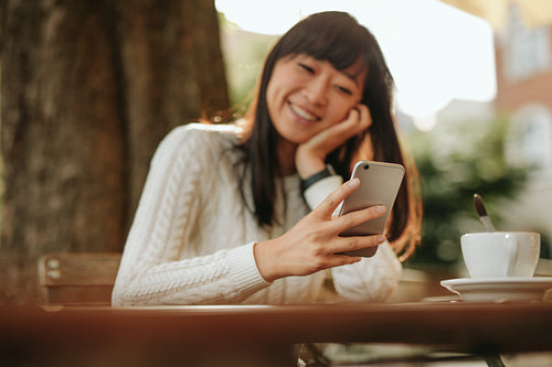 Smiling woman using smartphone in cafe