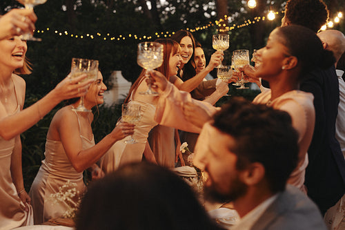 Friends raising glasses in joyful toast at outdoor dinner party