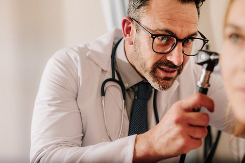 ENT physician examining patient's ear with an otoscope
