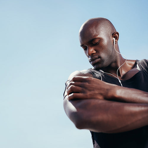 African muscular man listening to music on mobile phone