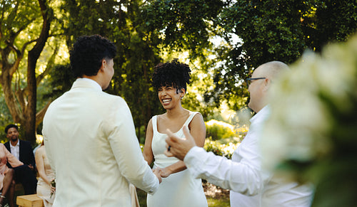 Outdoor wedding ceremony featuring a smiling bride with friends and family surrounding
