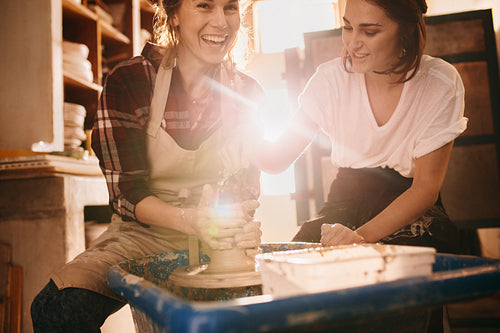 Two women at a pottery workshop making clay pots