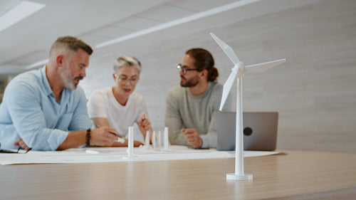 Sustainable engineering in a creative office: Business people collaborating on a wind turbine design