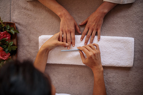 Woman receiving a manicure by beautician in spa salon