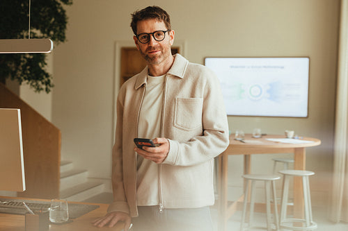 Man handles mobile communication at a desk in office