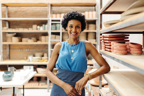 Successful female potter smiling at the camera in her shop