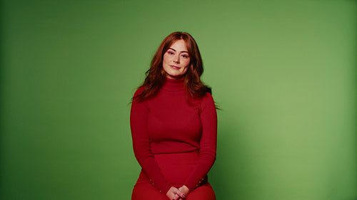 Young woman smiling in a red dress in front of a green screen