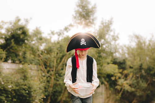 Boy as a pirates walking with fish bowl 