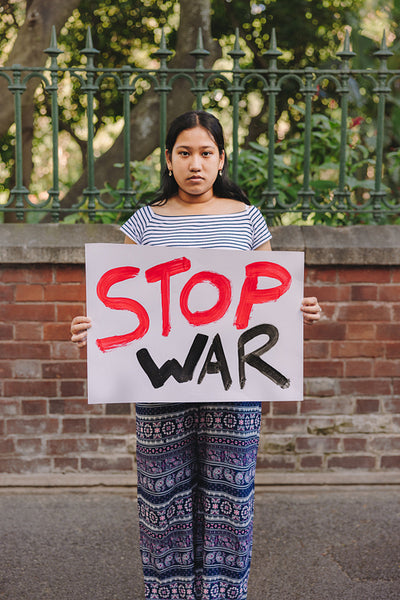 Ethnic girl holding an anti-war poster outdoors