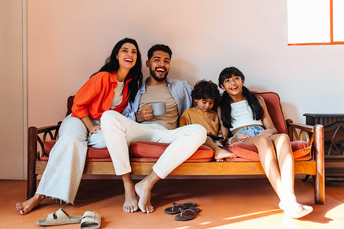 Smiling family relaxing together on a couch in a cozy home
