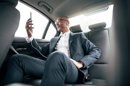 Businessman sitting in car looking at his mobile phone