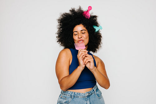 Woman with Afro hair singing while holding a fork comb