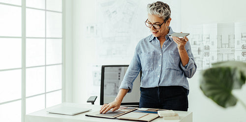 Mature designer calling a client to discuss her progress in their project