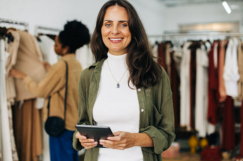 Portrait of a female clothing store owner holding a tablet in her shop