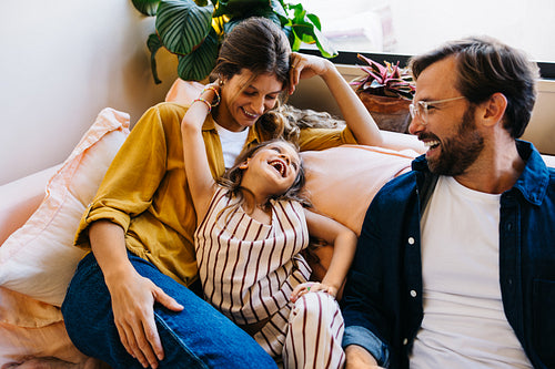 Family laughs together on a cozy couch