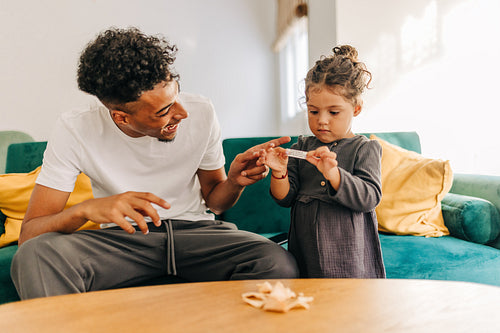 Happy young father playing with his daughter at home