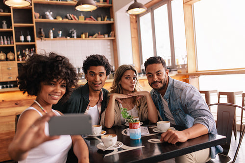 Small group of friends taking selfie at cafe