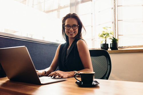 Young woman working on laptop computer in office.
