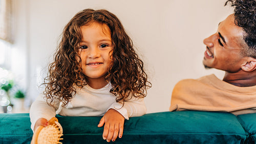 Cute young girl smiling at the camera while sitting on a couch