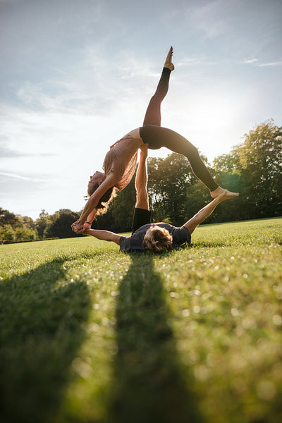 Couple doing acrobatic yoga on grass