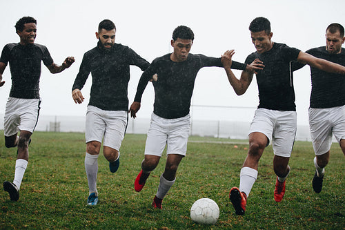 Men playing soccer in rain