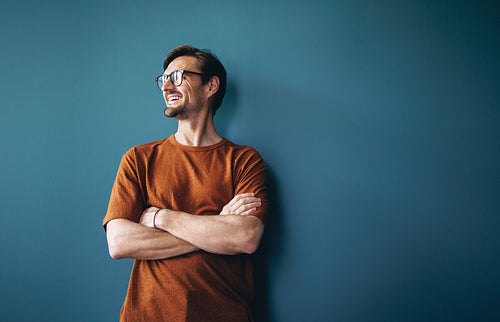 Career success: Business man smiling against a blue wall in a corporate office