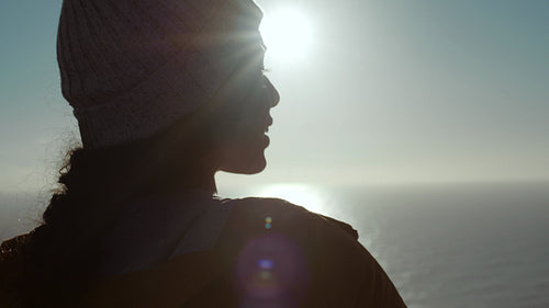 Smiling woman standing at the hill top at sunset  