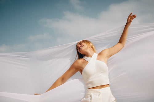 Young woman enjoying freedom outdoors with fabric in sunlight and blue skies