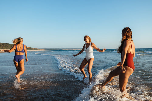 Three friends play joyfully in the ocean at a scenic beach.