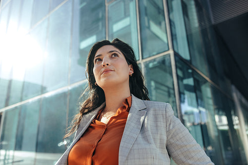 Thoughtful businesswoman looking up while standing outdoors