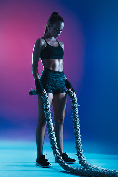 Fitness woman exercising with battle ropes