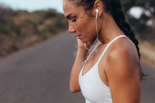 Sportswoman taking break and listening music