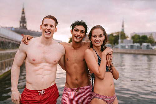 Young people in swimwear standing by a lake