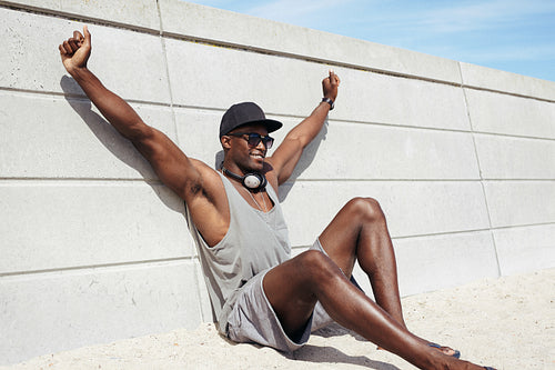 Muscular young man sitting on beach looking happy