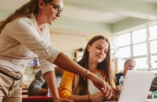 Teacher helping student in classroom