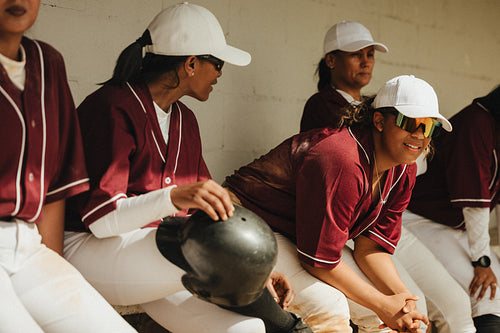 Confident female baseball players in dugout wearing matching uniforms
