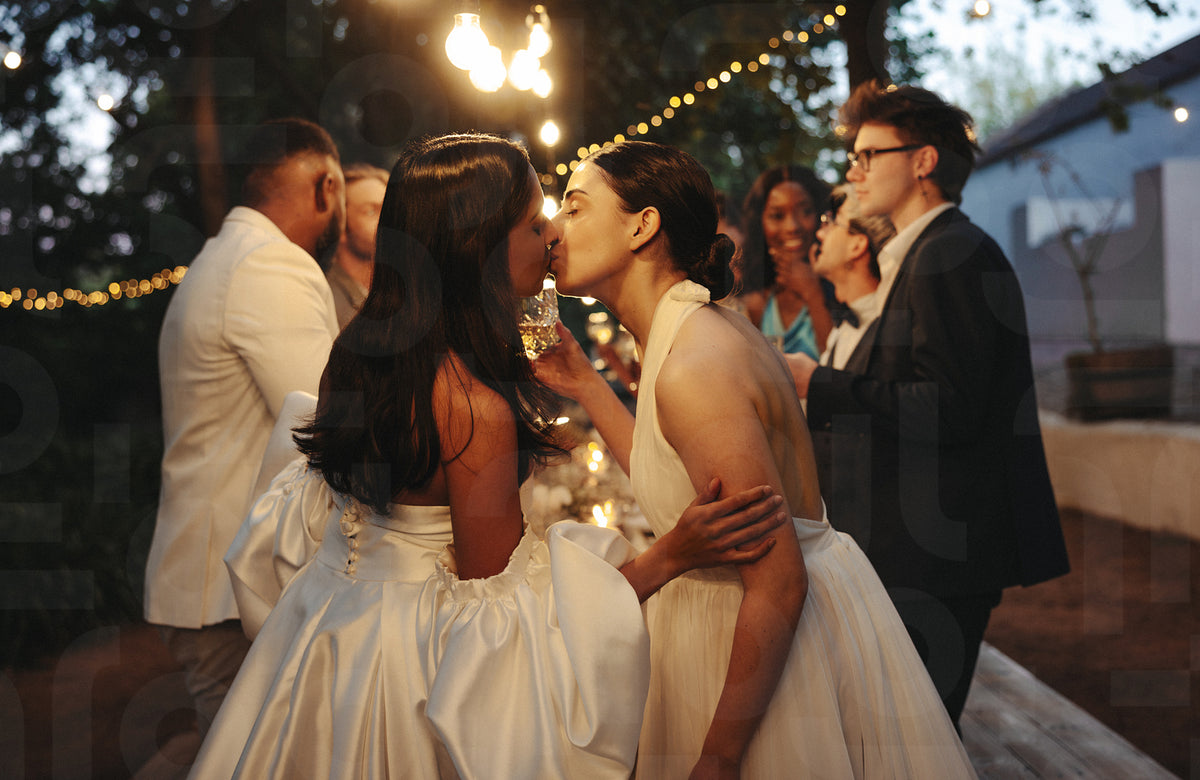 Two brides kissing during outdoor LGBTQ wedding party Jacob Lund