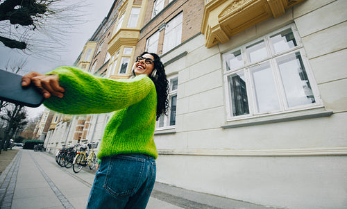 Streaming woman walks on an urban street with music on her smartphone