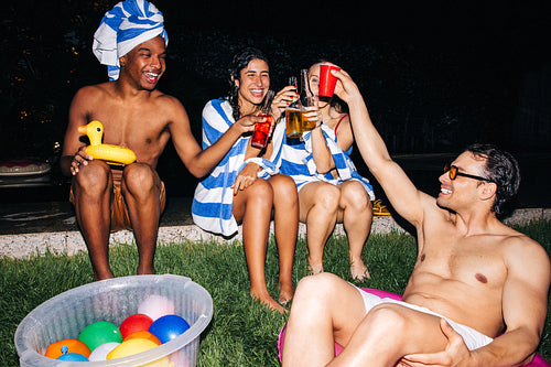 Friends at poolside night party with drinks and laughter