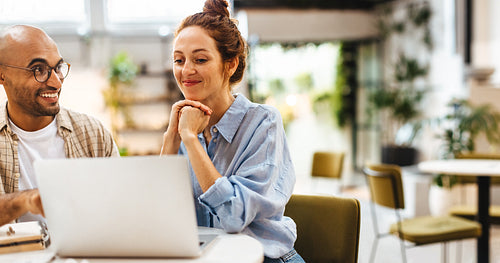 Two work colleagues using a laptop together in a coworking space