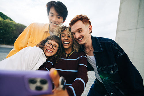 Friends taking a smiling selfie outdoors in urban setting