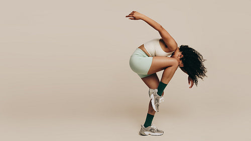 Sportiness in the studio: Woman with a flexible body performing a workout pose
