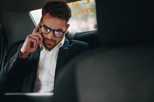 Businessman talking on mobile phone sitting in a taxi
