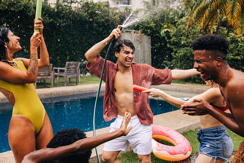 Friends enjoy a playful poolside water fight