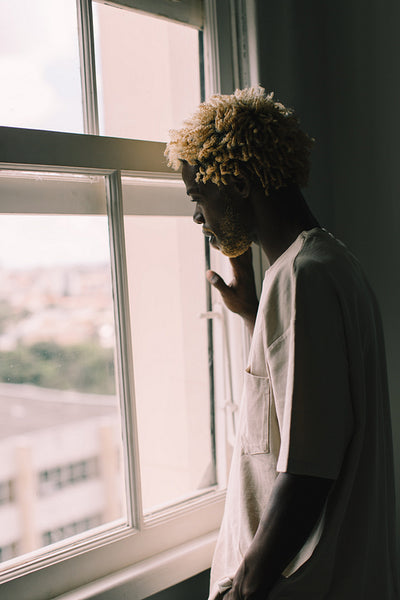 Young man looking outside the window at home