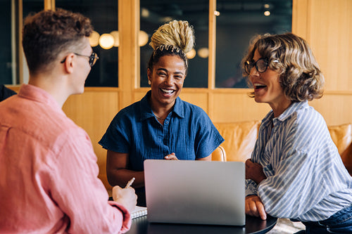 Smiling team of three professionals having a collaborative meeting in a modern office