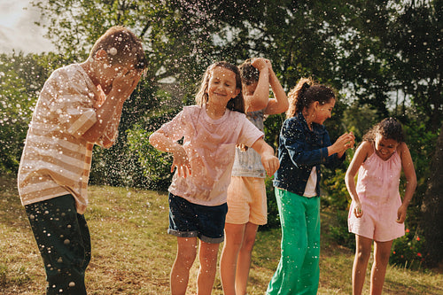 Children playing joyfully outdoors with water splashes on a sunny day
